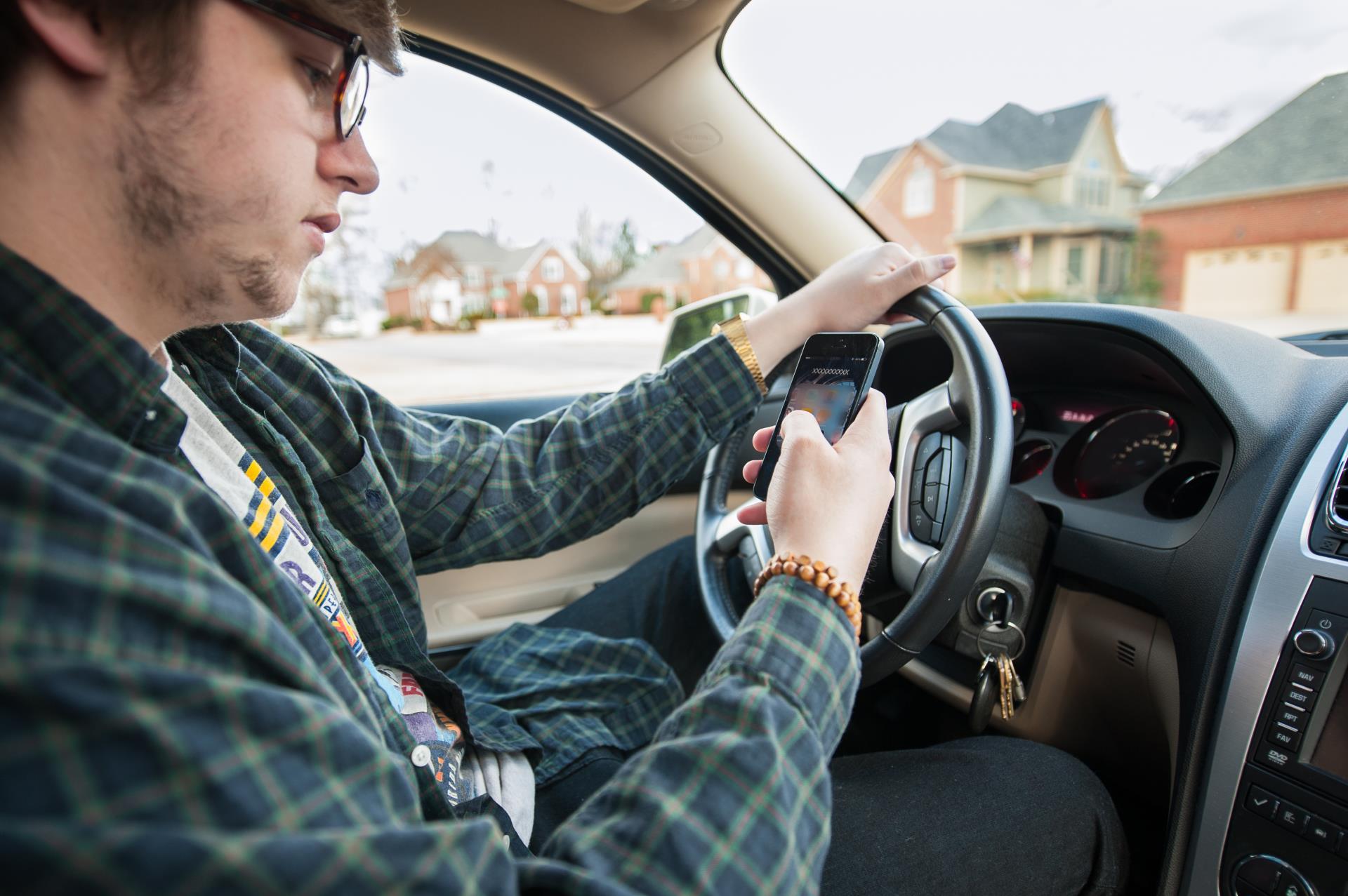 Image of young man texting while driving a vehicle